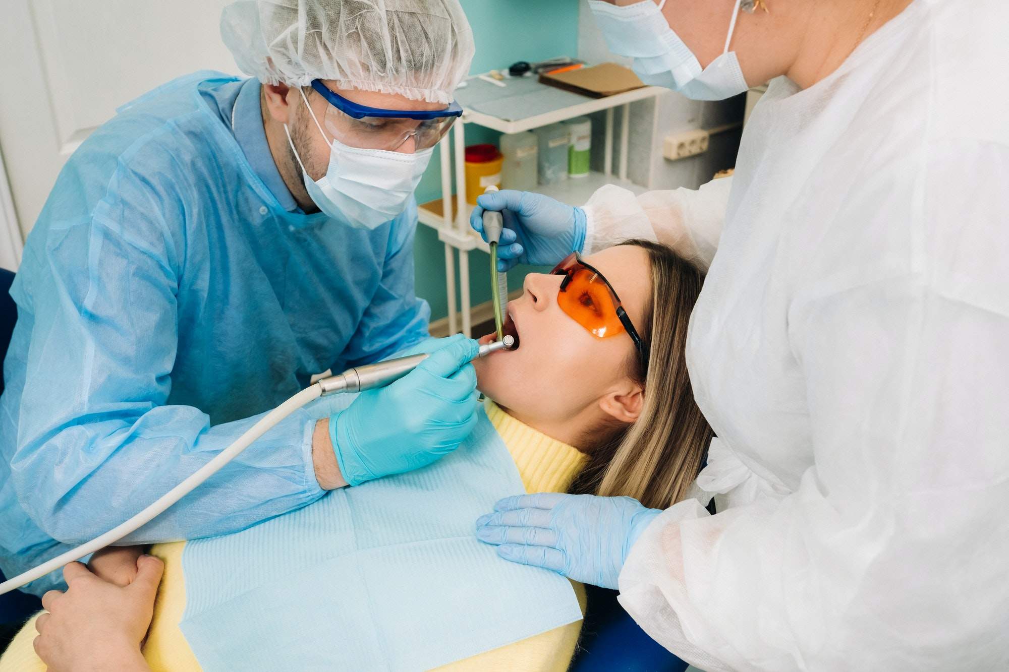 Naples Dentists 3 a male dentist with dental tools drills the teeth of a patient with an assistant the concept of.jpg